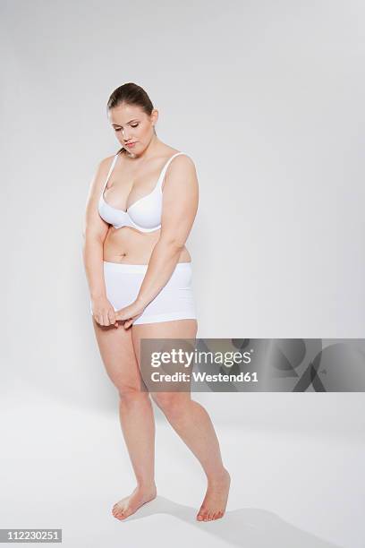 young chubby woman standing and looking down - woman standing looking down stock pictures, royalty-free photos & images