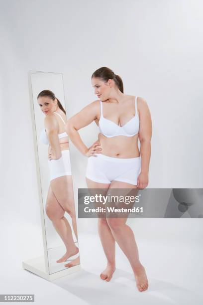 germany, cologne, young woman looking herself into mirror - woman-looking-into-mirror-full-body stock pictures, royalty-free photos & images
