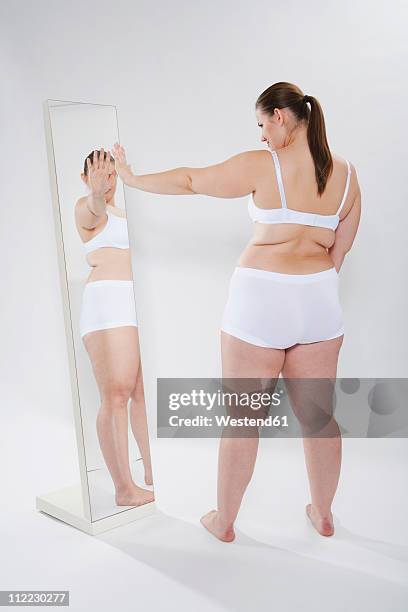 germany, cologne, young woman looking herself into mirror - woman-looking-into-mirror-full-body stock pictures, royalty-free photos & images