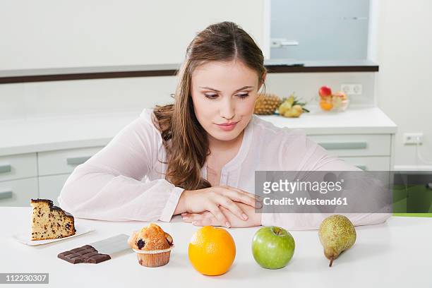 germany, cologne, young woman is confused between fruits and sweets - temptation stock pictures, royalty-free photos & images