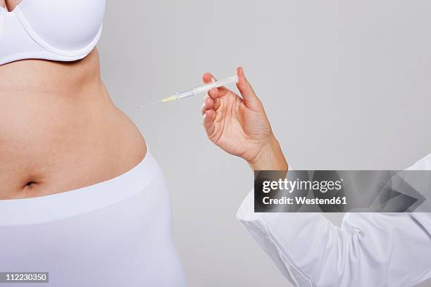 germany, cologne, mid adult woman giving injection to young woman - abspecken stock-fotos und bilder