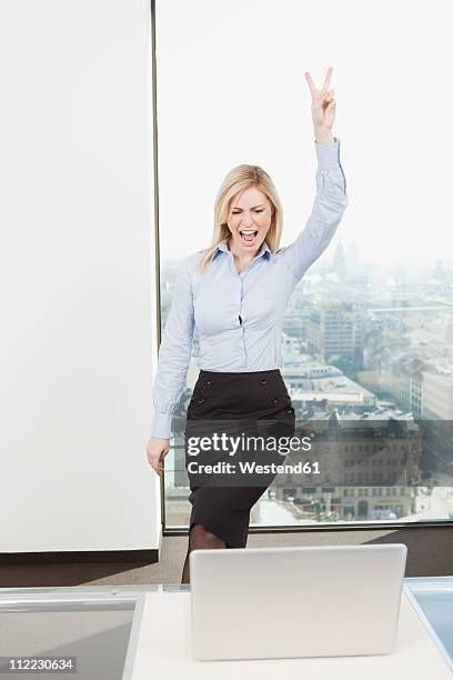 germany, frankfurt, business woman showing v sign - blonde cheering stock-fotos und bilder