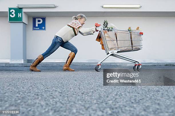 germany, young woman pushing shopping cart - spingere carrello foto e immagini stock