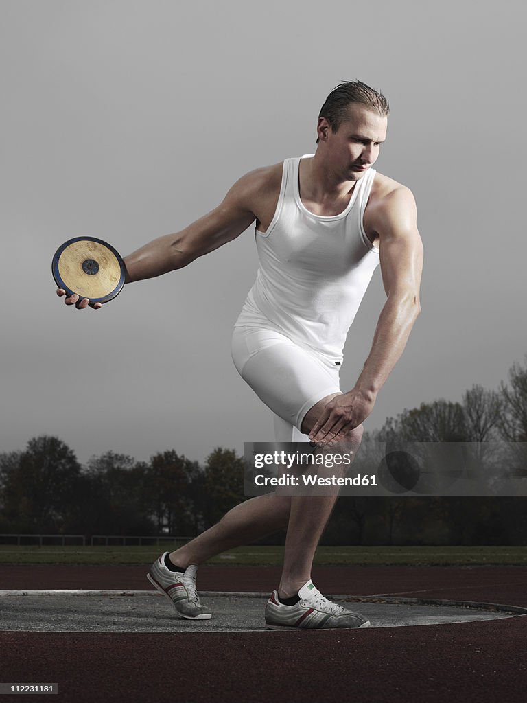 Germany, Augsburg, Young man holding discus