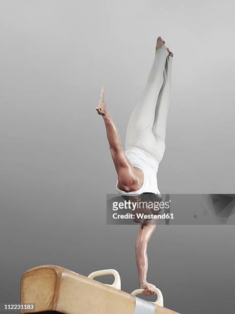 germany, augsburg, young man doing headstand on pommel horse - male gymnast stockfoto's en -beelden