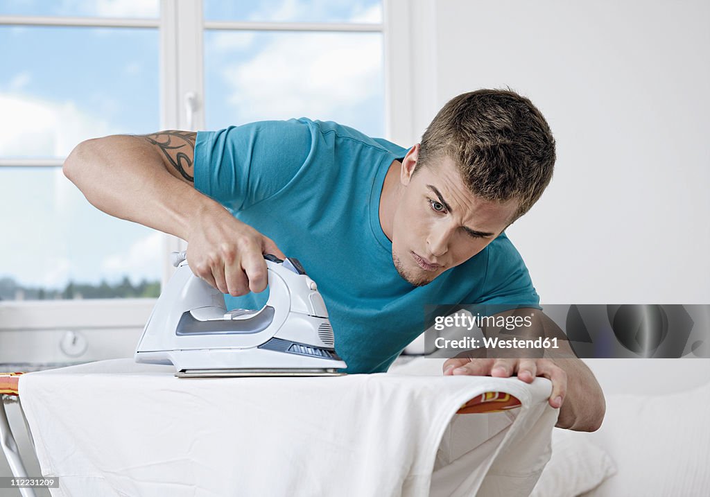 Germany, Augsburg, Man ironing shirt