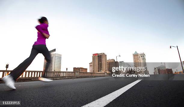 a teenage girl runs on the street away from the camera towards downtown birmingham, alabama. (motion blur) - birmingham alabama ストックフォトと画像