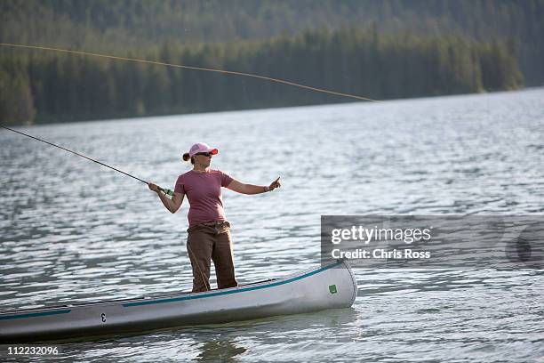 a woman casts her flyline while on a canoe. - small boat stock pictures, royalty-free photos & images