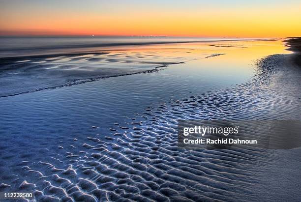 a sunset is reflected at low tide at coligny beach on hilton head island, south carolina. - hilton head photos et images de collection