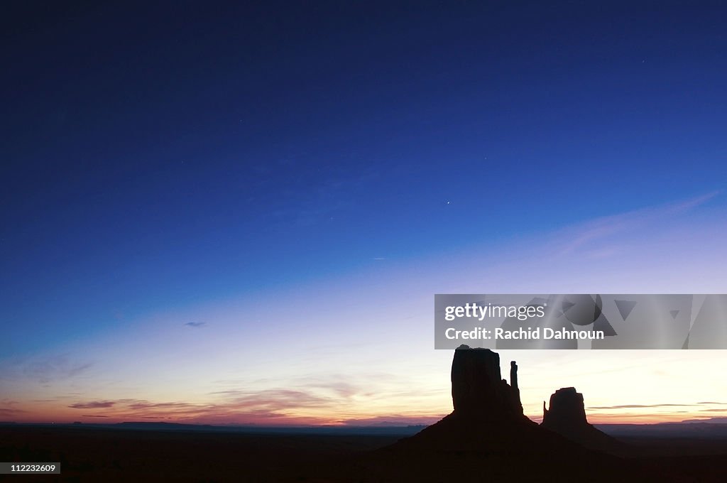 The famous Mittens are silhouetted at sunrise in Monument Valley, Arizona