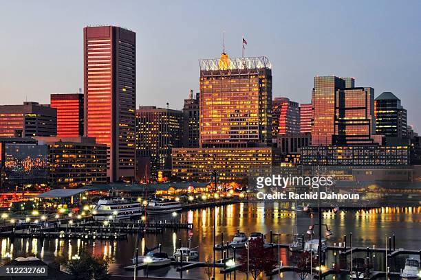 the sunset reflects off the windows of the baltimore city skyline at dusk, maryland. - baltimore maryland imagens e fotografias de stock