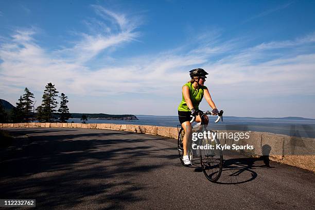 a female cyclist rides her road bike in maine's acadia national park. - acadia national park stock pictures, royalty-free photos & images