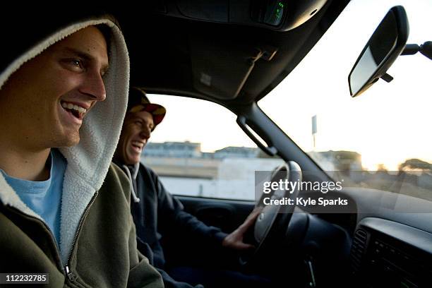 two male surfers share a laugh while driving to the beach in ventura, california. - auto interieur stockfoto's en -beelden