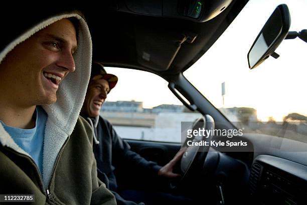 two male surfers share a laugh while driving to the beach in ventura, california. - friends inside car imagens e fotografias de stock