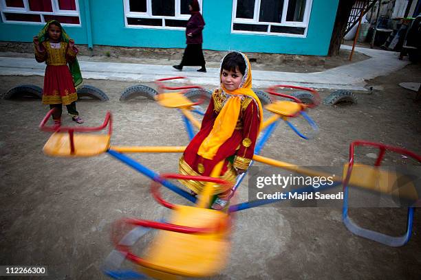 An Afghan girl plays on a merry-go-round as they take part in a performance to celebrate the second "World Circus Day" on April 16, 2011 in Kabul,...