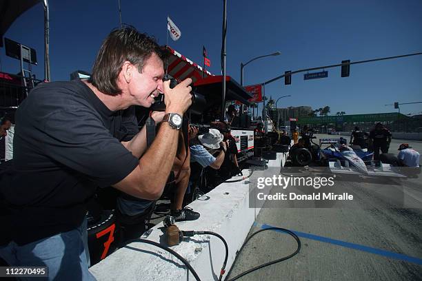 Former MLB pitcher Randy Johnson shoots Helio Castroneves, driver of the Auto Club of Southern California Team Penske Dallara Honda, from the pits...