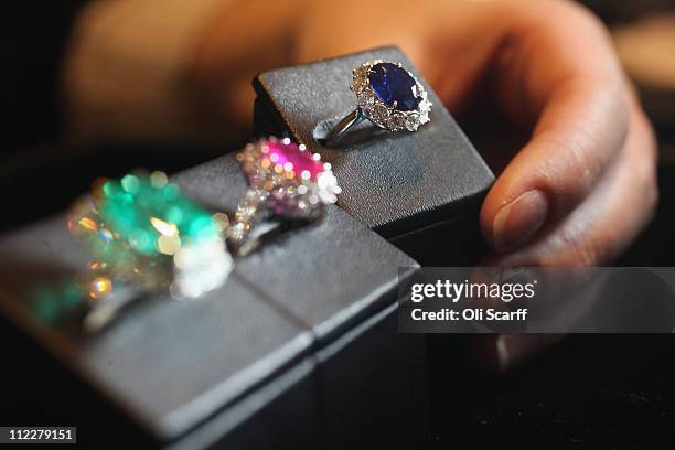 Woman examines emerald, ruby and sapphire rings set in the Garrard Royal Cluster in Garrard's flagship store in Mayfair on April 6, 2011 in London,...