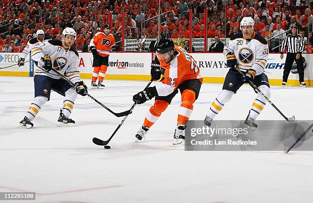 Ville Leino of the Philadelphia Flyers skates the puck between Marc-Andre Gragnani and Rob Niedermayer of the Buffalo Sabres in Game One of the...