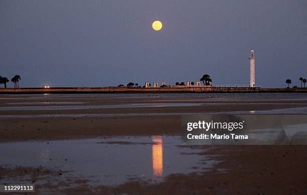 The full moon rises over Biloxi's beach and lighthouse April 17, 2011 in Biloxi, Mississippi. Biloxi's beaches continue to be impacted by tar balls...