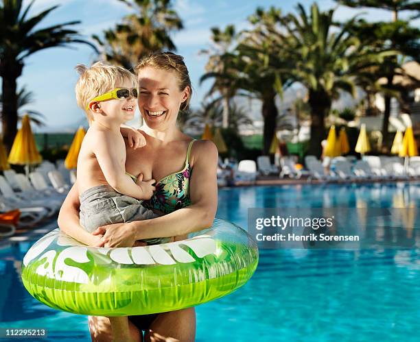 mother holding son in a swimming ring by the pool - tenerife spain stock pictures, royalty-free photos & images