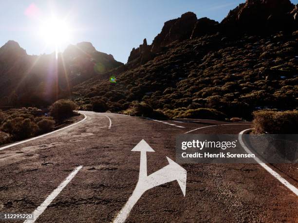 arrow indicating side road in mountain landscape - intersection stock pictures, royalty-free photos & images