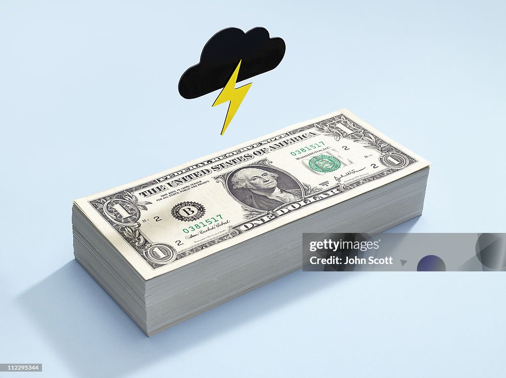 Dollar bills with a dark cloud above