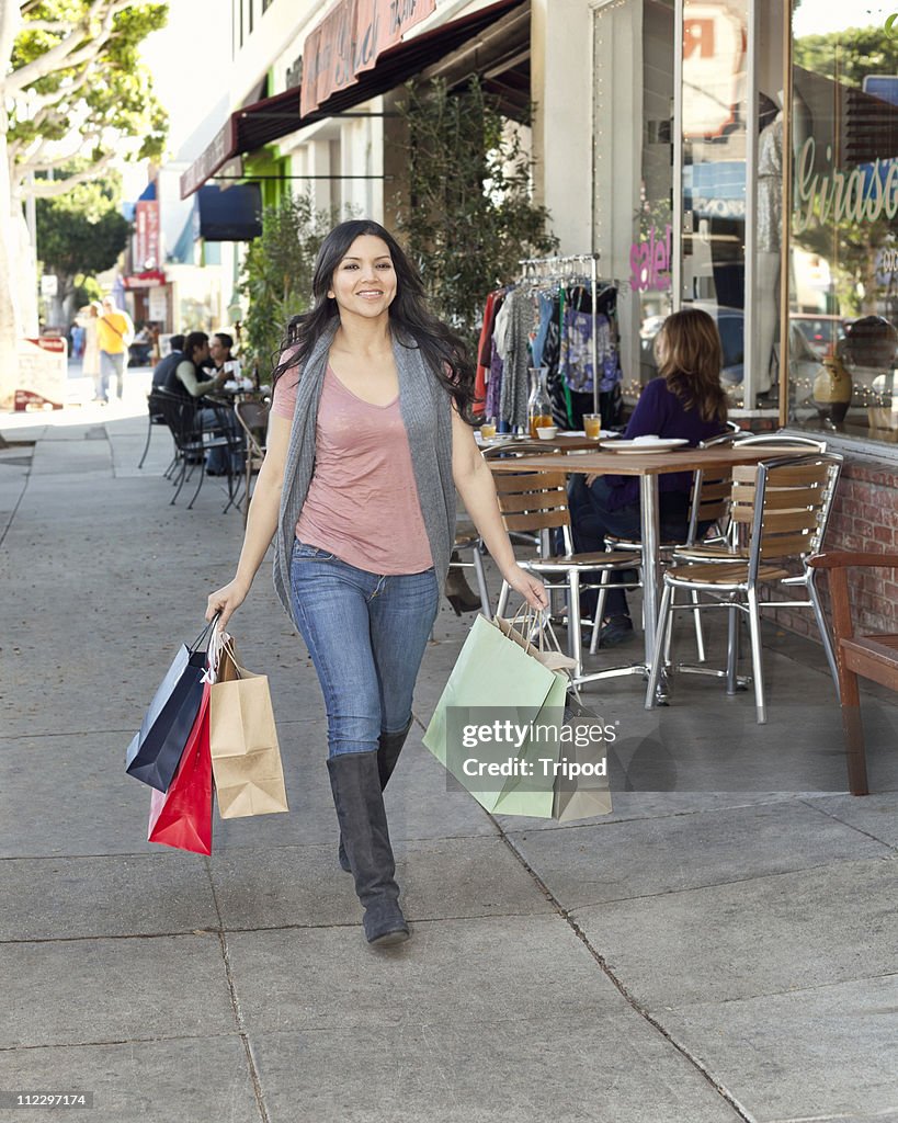 Woman walking by stores holding shopping bags