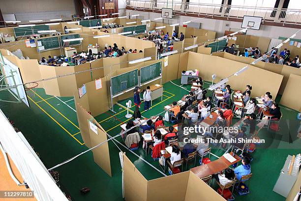 School pupils have lessons in the gymnasium because of the walls of the classroom building were heavily damaged by the earthquake and tsunami at...