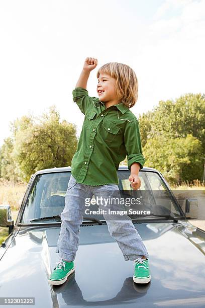 boy standing on hood of car - boy jeans stockfoto's en -beelden