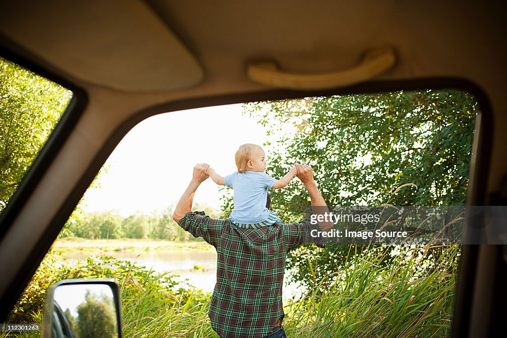 Father with son on shoulders, viewed from a car