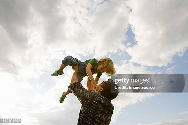 father lifting son up to the sky - only kids at sky stockfoto's en -beelden