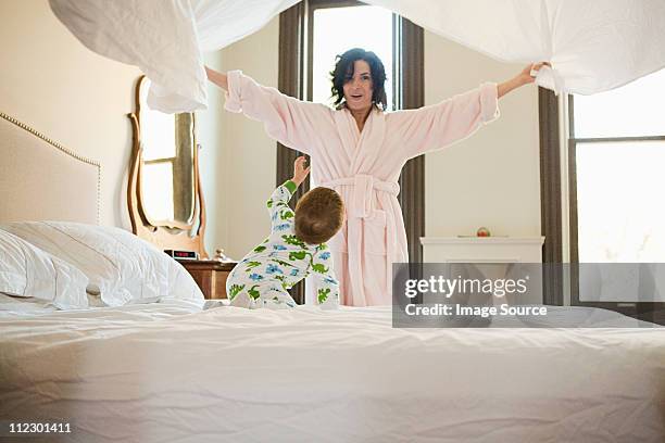 mother and baby son making bed - woman in bathrobe stock pictures, royalty-free photos & images