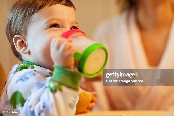 baby boy drinking from beaker - laboratoriumglas stockfoto's en -beelden
