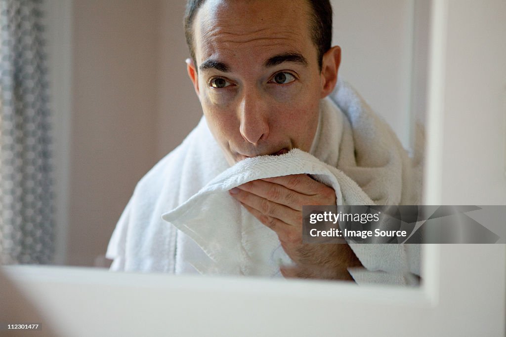 Man shaving in bathroom mirror