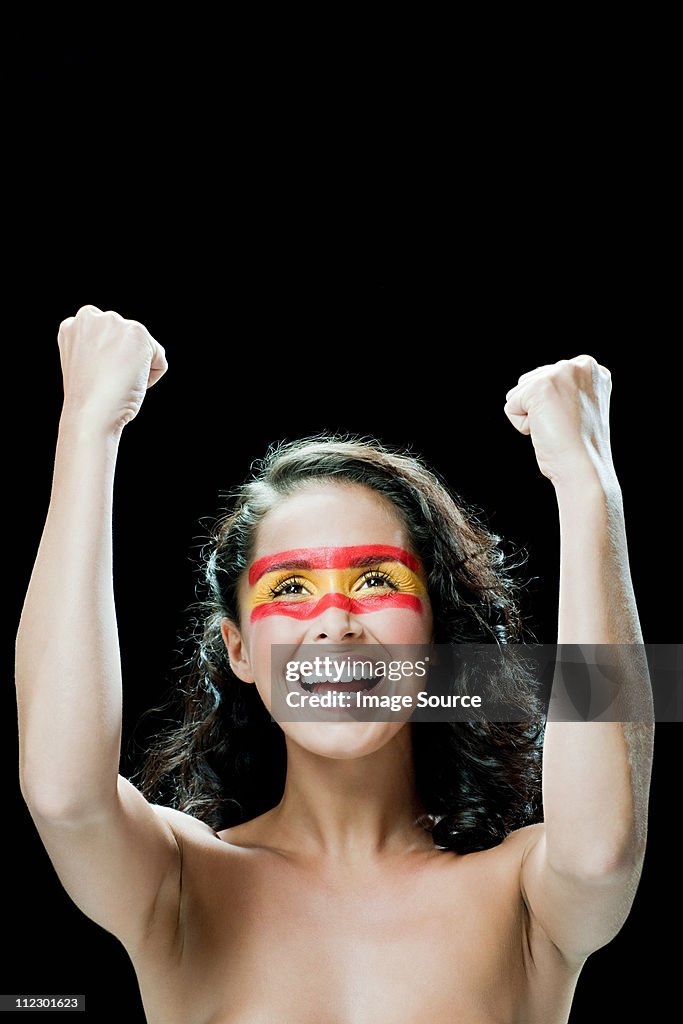 Woman with Spanish flag painted on face, cheering