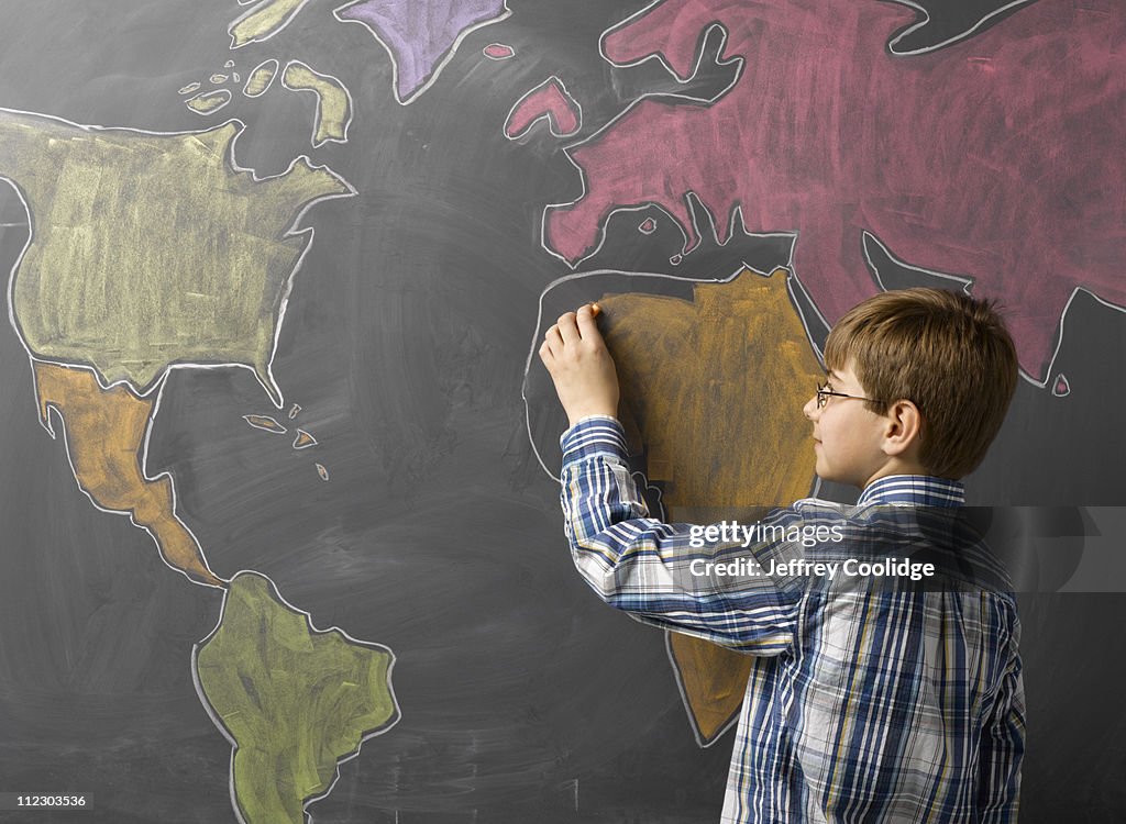 Child Drawing World Map on Blackboard
