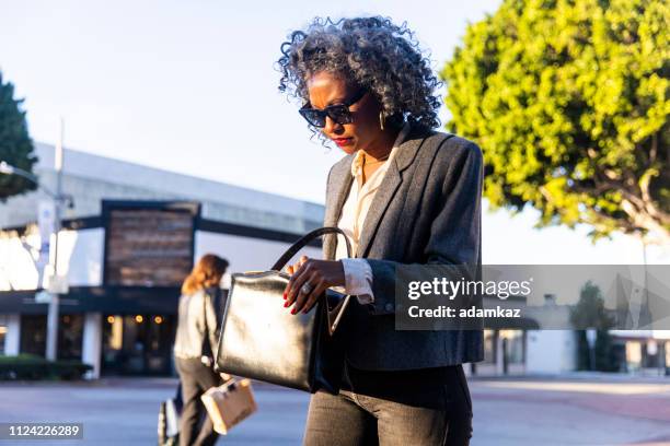 woman looking in her purse - finding gray hair stock pictures, royalty-free photos & images