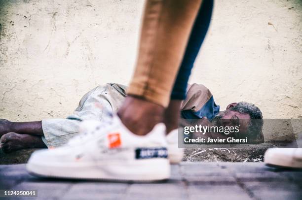 hombre sin hogar durmiendo en la calle y gente caminando. camagüey, cuba. - durmiendo stock pictures, royalty-free photos & images