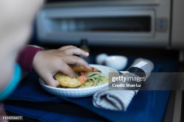 child taking food with hand in business class on plane. - toddler at airport stock-fotos und bilder