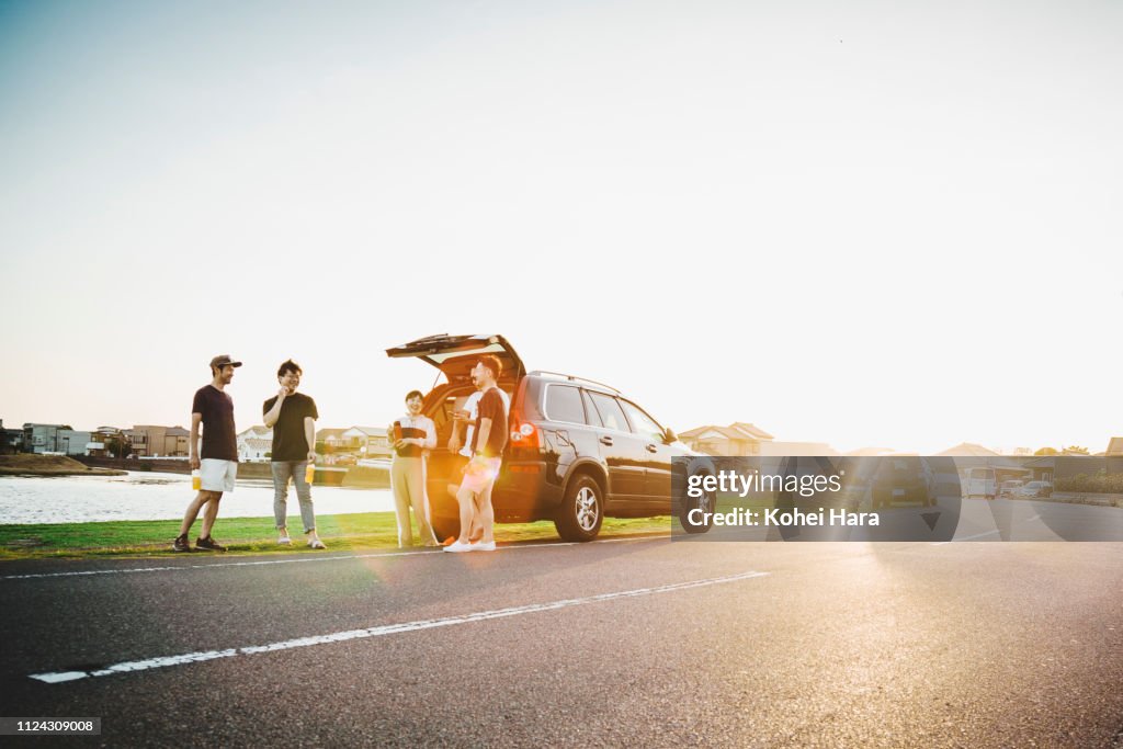 Group of friends talking and getting relaxed by car outdoors