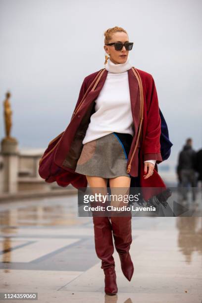 Elina Halimi, wearing a white jumper, brown and black mini skirt, burgundy boots, burgundy coat and scarf, is seen outside Elie Saab show during...