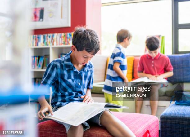 boy reading book in library at elementary school - picture book stock pictures, royalty-free photos & images