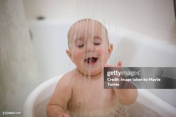 baby boy in the bathtub playing with water - bad haircut stockfoto's en -beelden