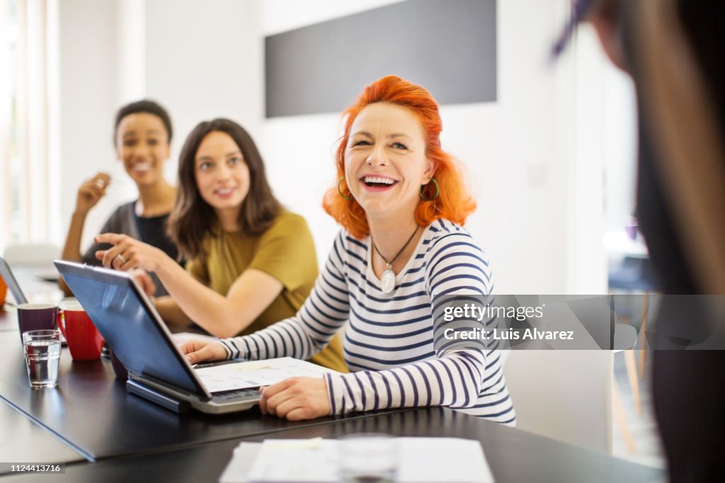 Mature woman smiling in meeting with colleagues