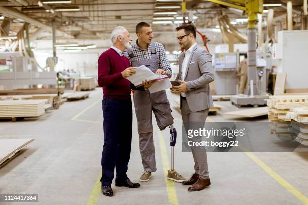 Three men standing and discuss in furniture factory