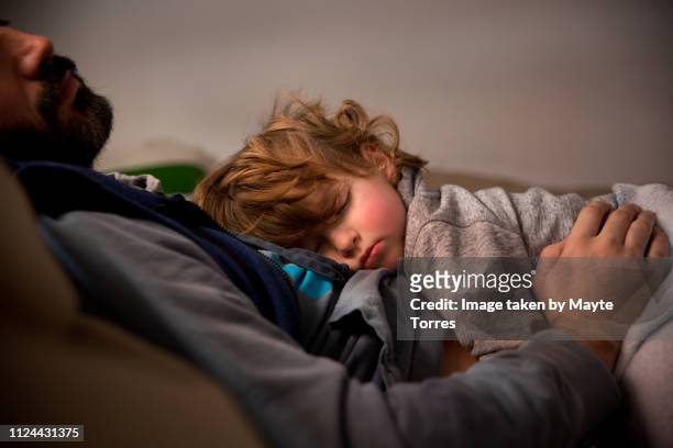 toddler having a nap with dad in the sofa - comodità foto e immagini stock
