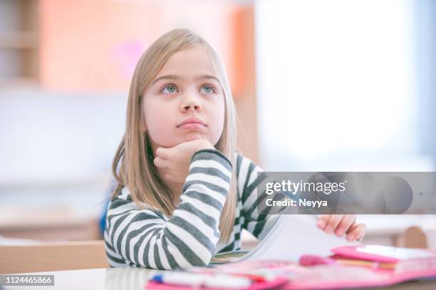 cute schoolgirl sitting in school classroom drawing - distraído imagens e fotografias de stock