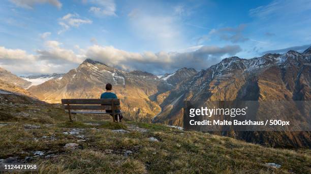 lone man sitting on bench in mountains - man on bench stock-fotos und bilder