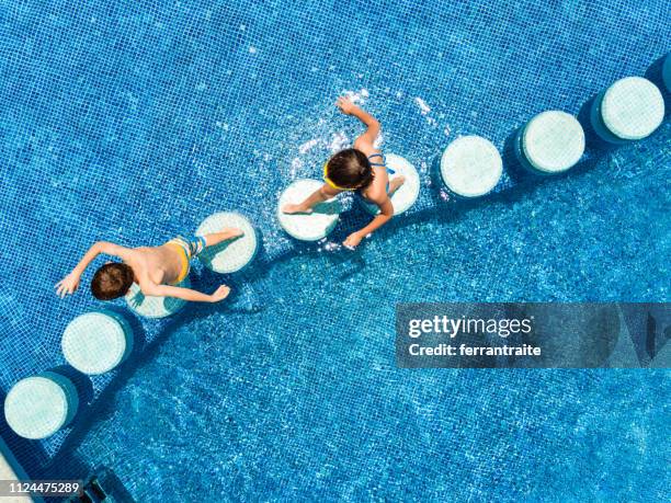 kinderen zwemmen in een zwembad - stepping stones stockfoto's en -beelden