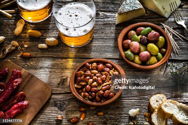 oliven, erdnüsse und bier von oben am rustikalen holztisch erschossen - beer nuts stock-fotos und bilder